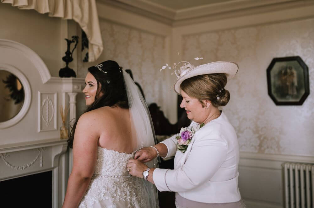 The mother of the bride zips her daughters dress.