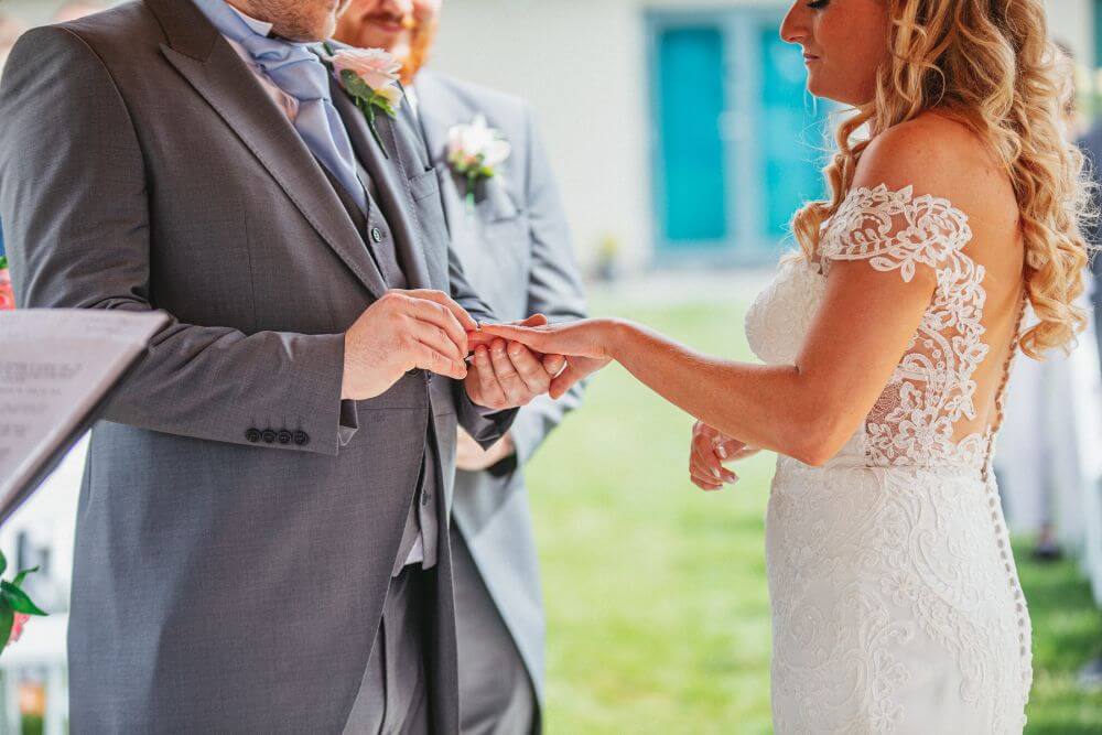The groom places the ring in the brides finger.