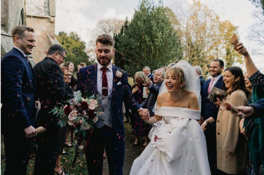 The guests throw petals to the couple as they laugh.