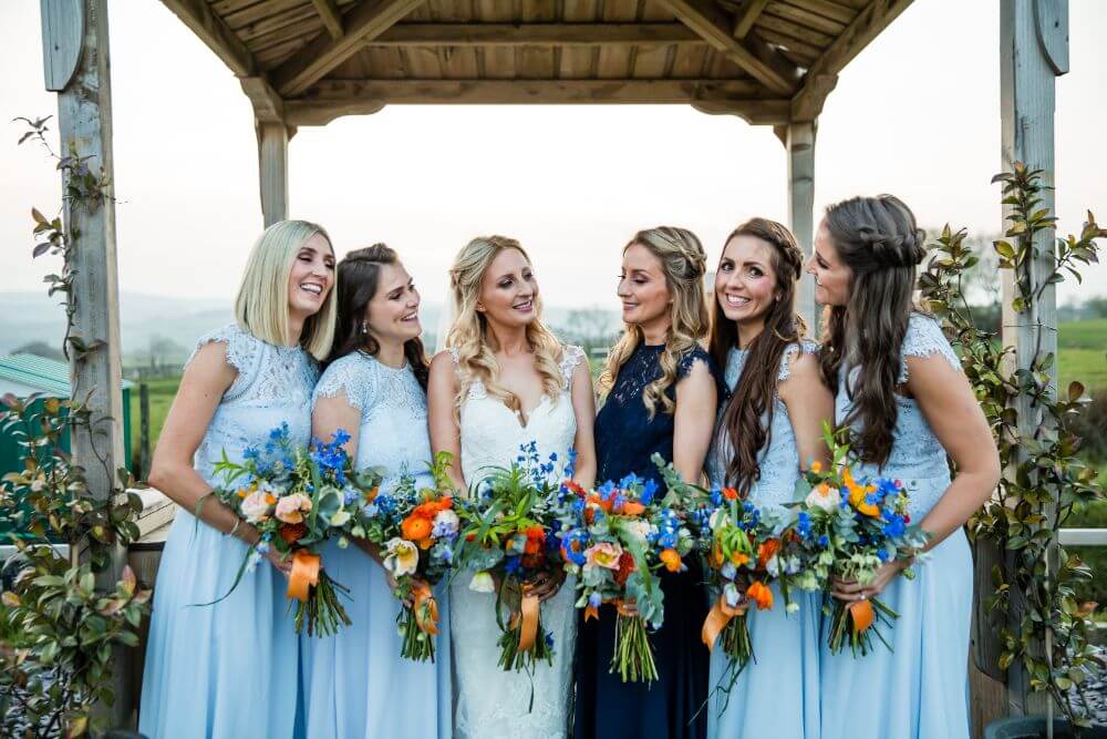 The bride poses with her bridesmaids dressed in blue.
