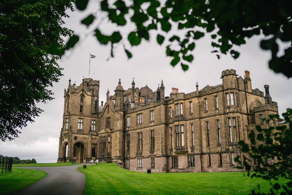 A big castle stands surrounded by well kept lawns.