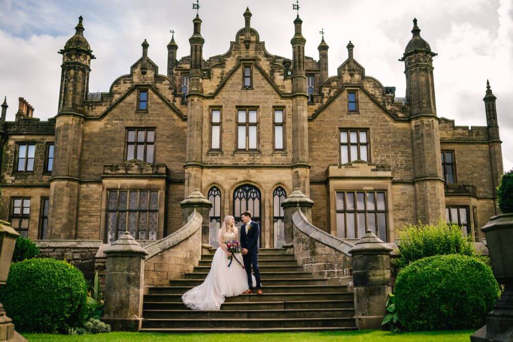 The bride and groom stand in the stone staircase outside.