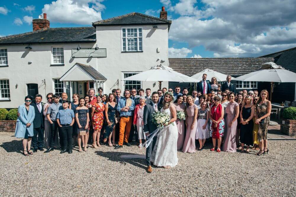 The couple and wedding guests stand in front of the house, that has a rustic yet contemporary style.