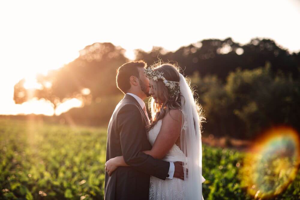 The bride and groom embracing with the sunset in the background.