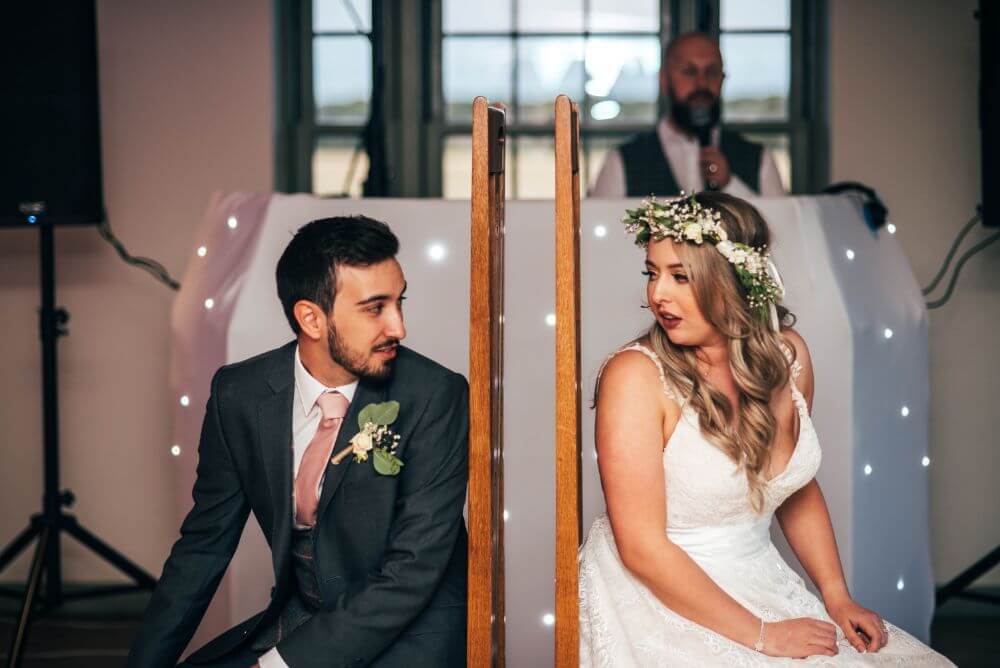 The bride and groom sit opposite each other with their backs turned.