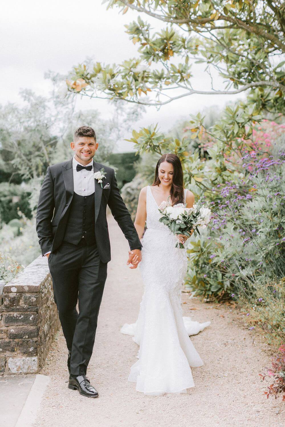 The bride and groom walking and holding hands.