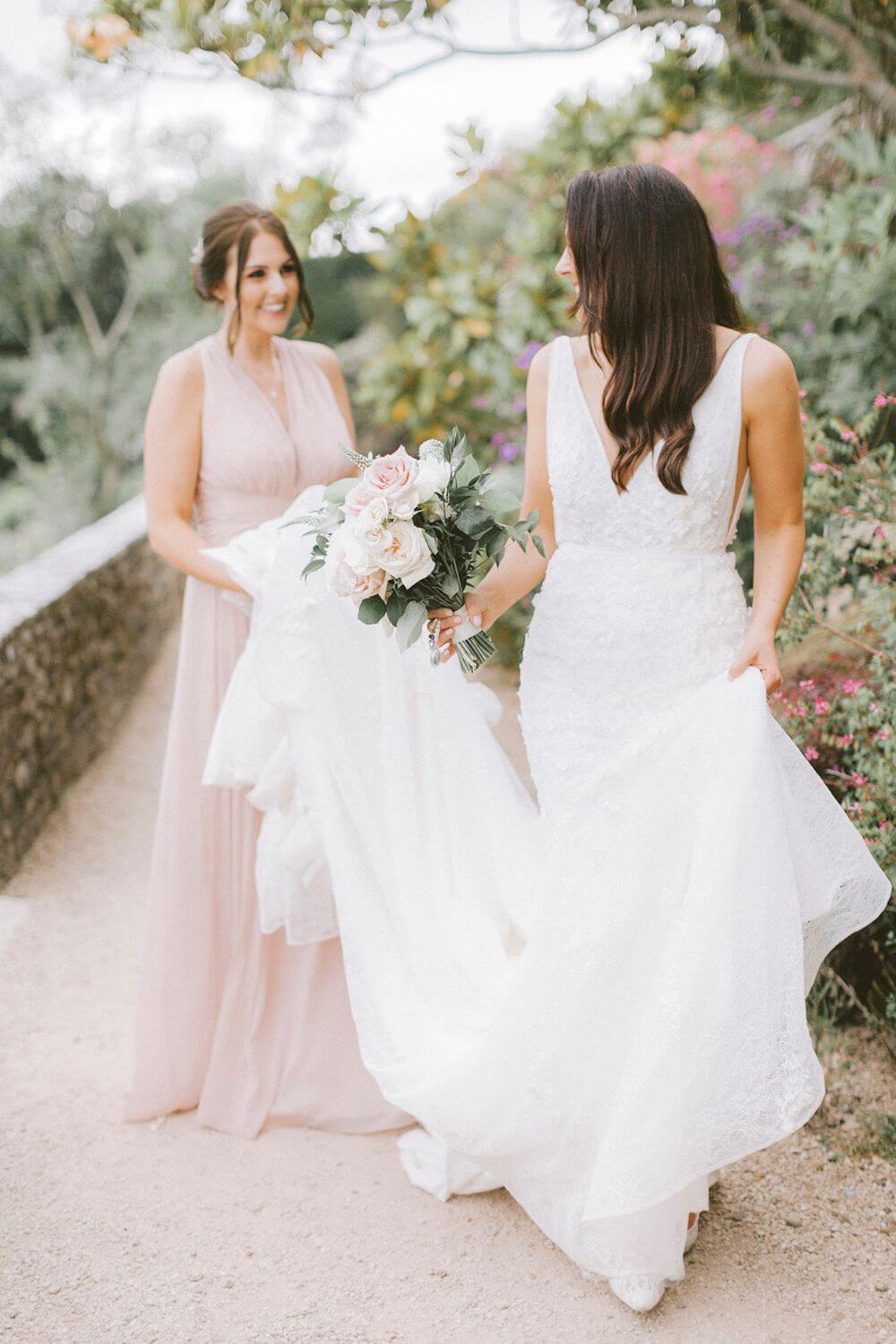 The bridesmaid holds the bride's dress.