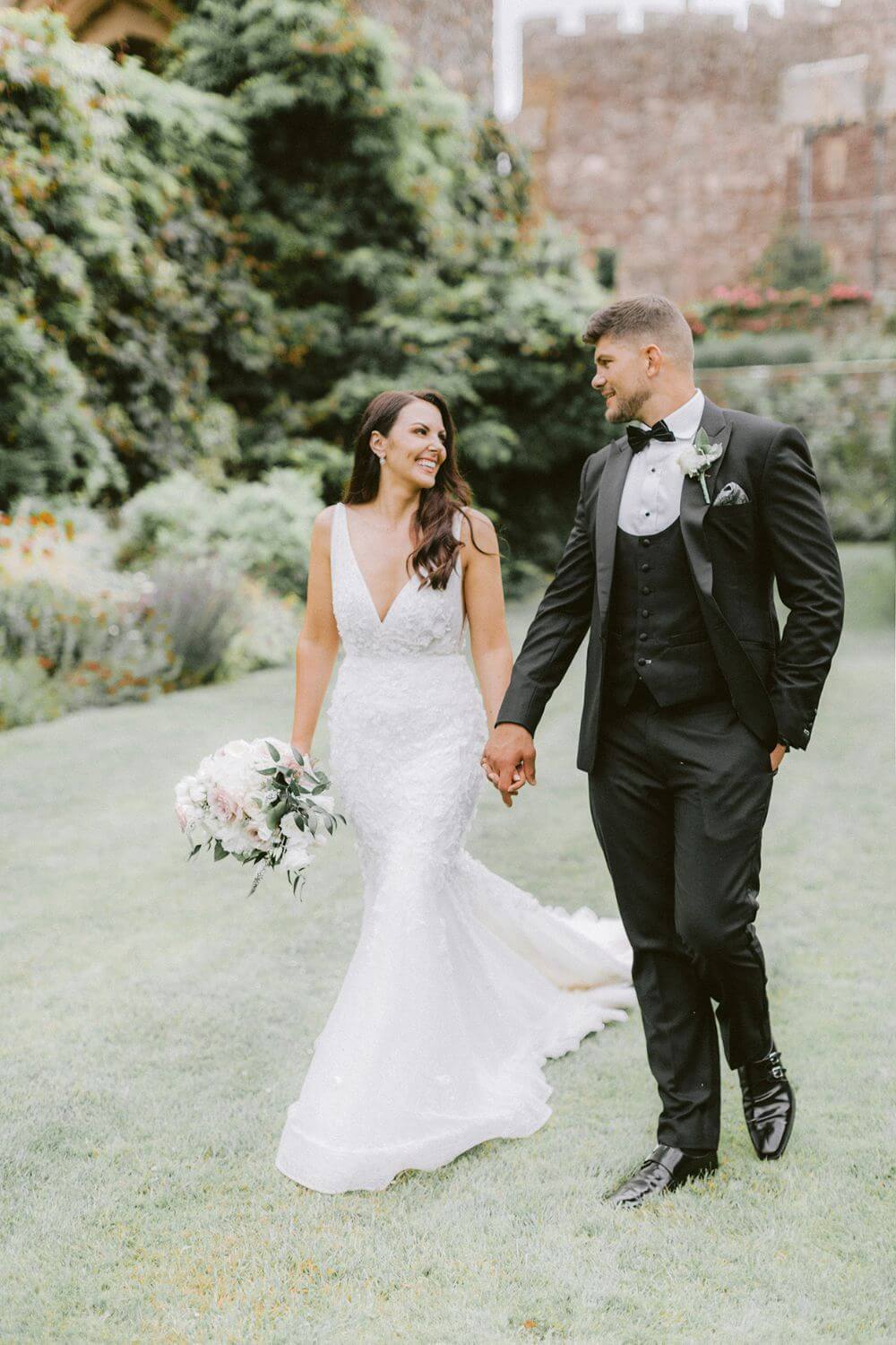 The bride and groom holding hands and smiling at each other.