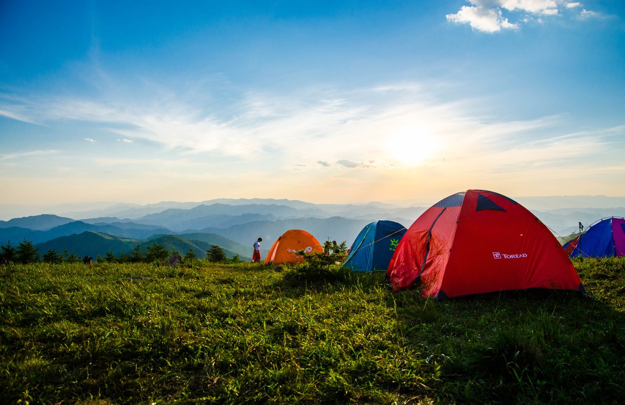 Dome camping tents and campers overlooking mountain ranges at sunrise