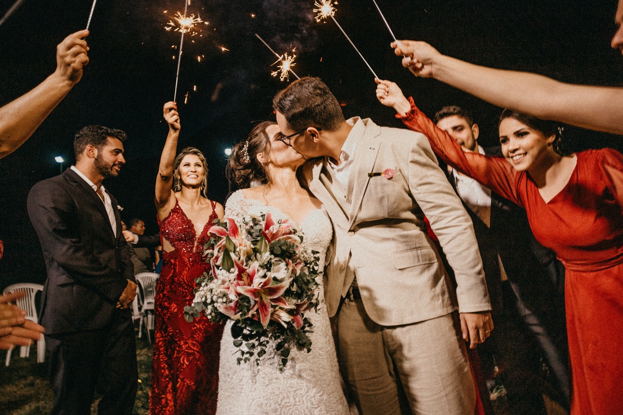 Married couple surrounded by wedding  party with sparklers