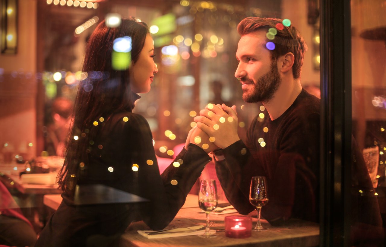 Cute couple in love holding hands on date at restaurant