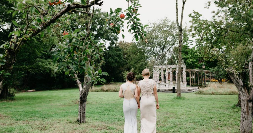 Brides walking into garden, backs of lace dresses showing