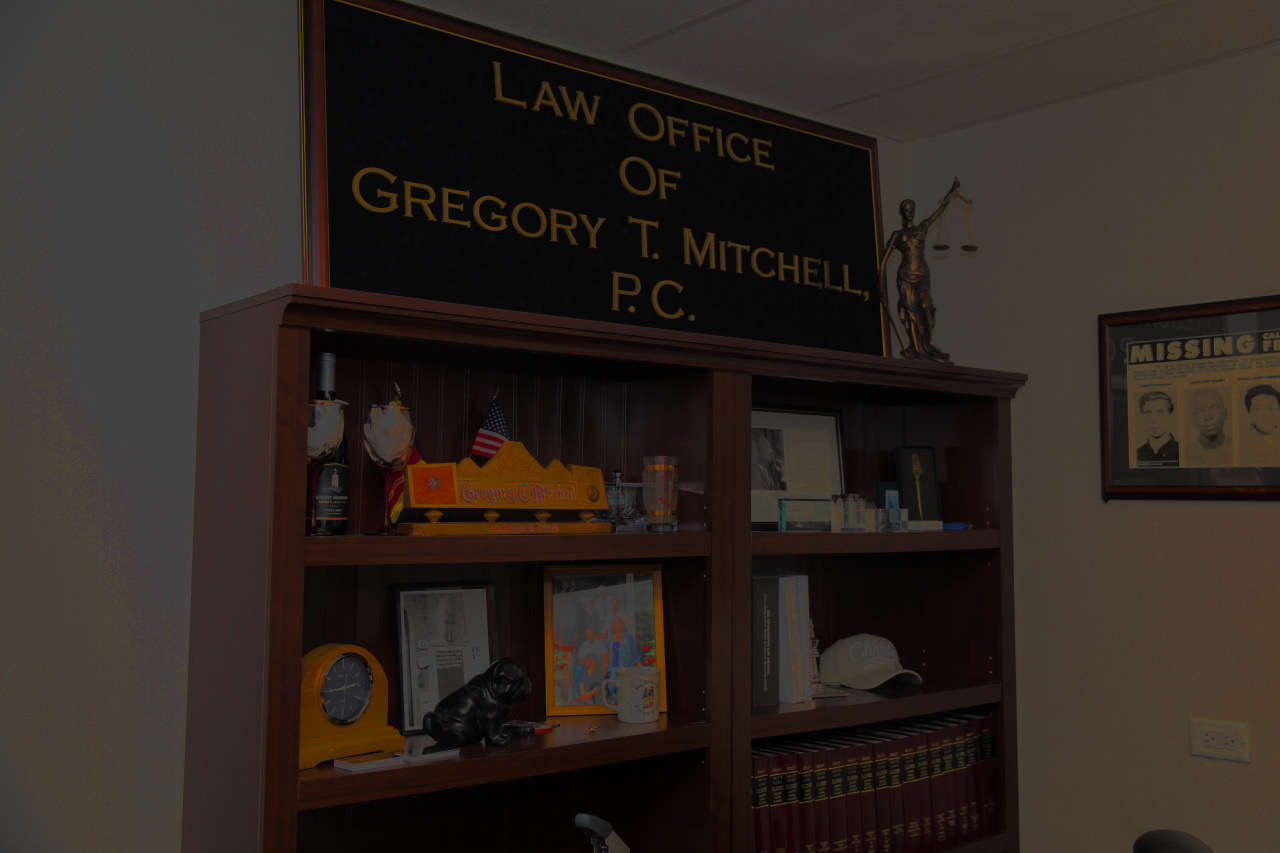 Law of Office of Gregory Mitchell plaque on bookshelf