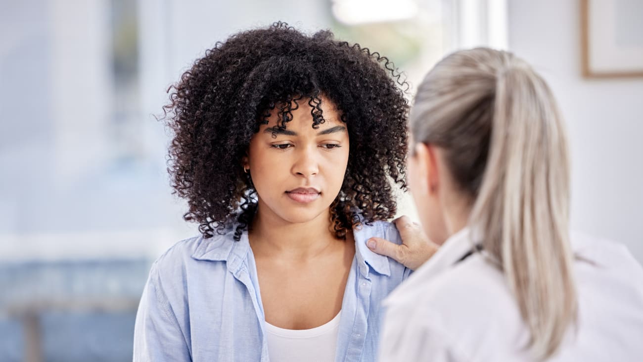 a young african amerian woman looking sad with a doctor