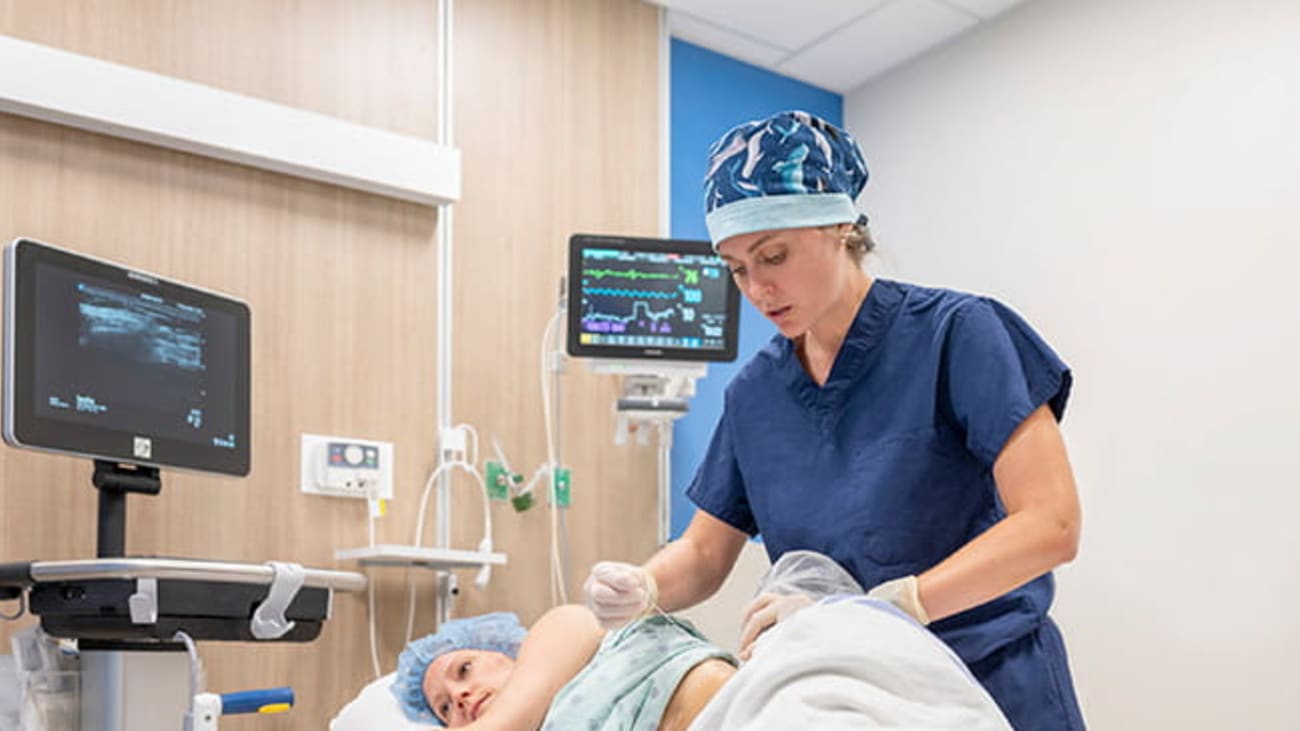 Nicole McCoy, M.D., uses a needle to perform a QL block on her patient prior to bone marrow harvesting. Credit: Brennan Wesley