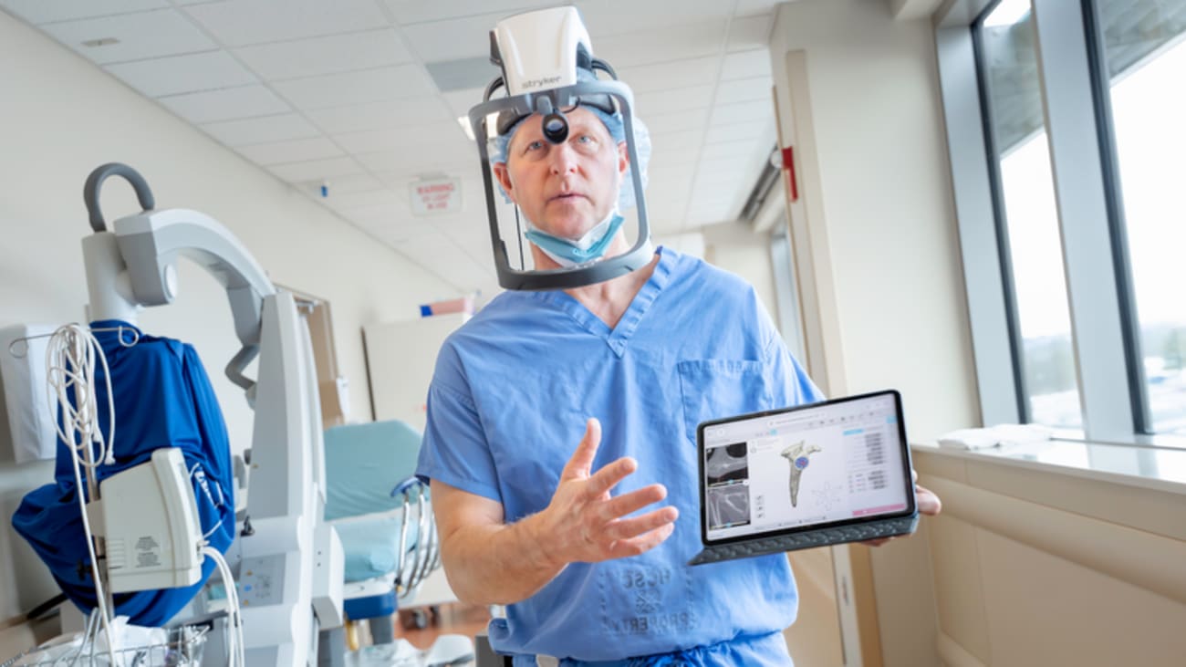 doctor in surgical attire holding a tablet showing a shoulder replacement device