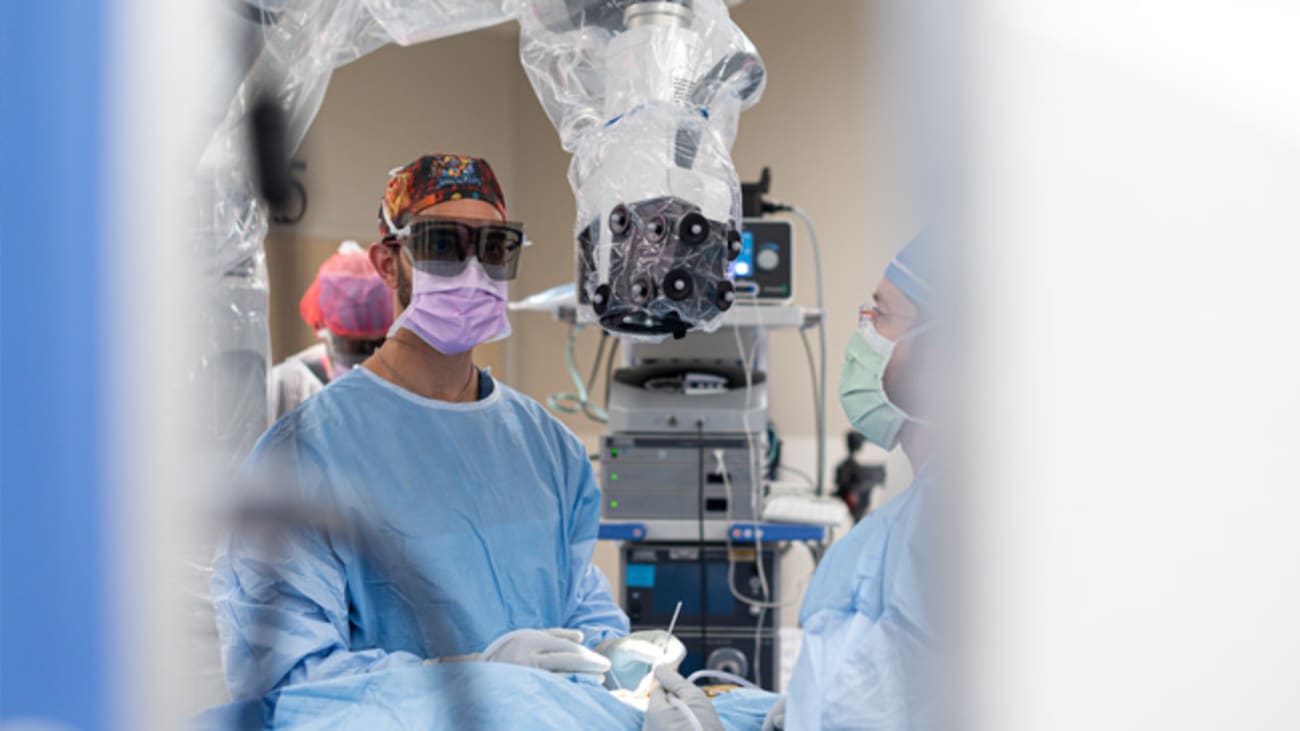 Ramin Eskandari, M.D., performs surgery using a Modus V digital robotic exoscope. With this device, he can look up at a screen instead of down into microscope eyepieces.