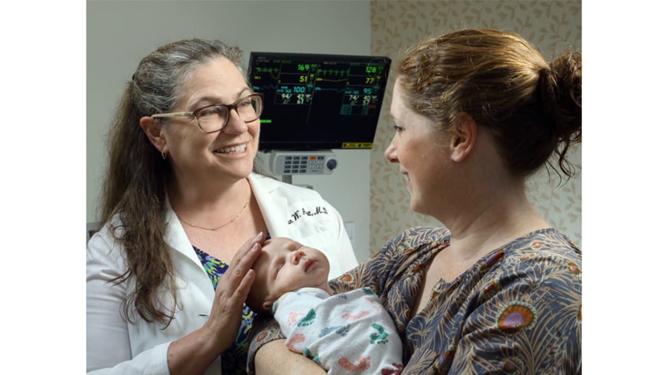 Neonatologist Susan Aucott with a young patient and mom.