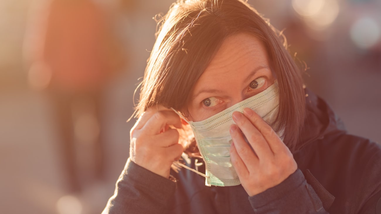 Woman putting on a disposable face mask.