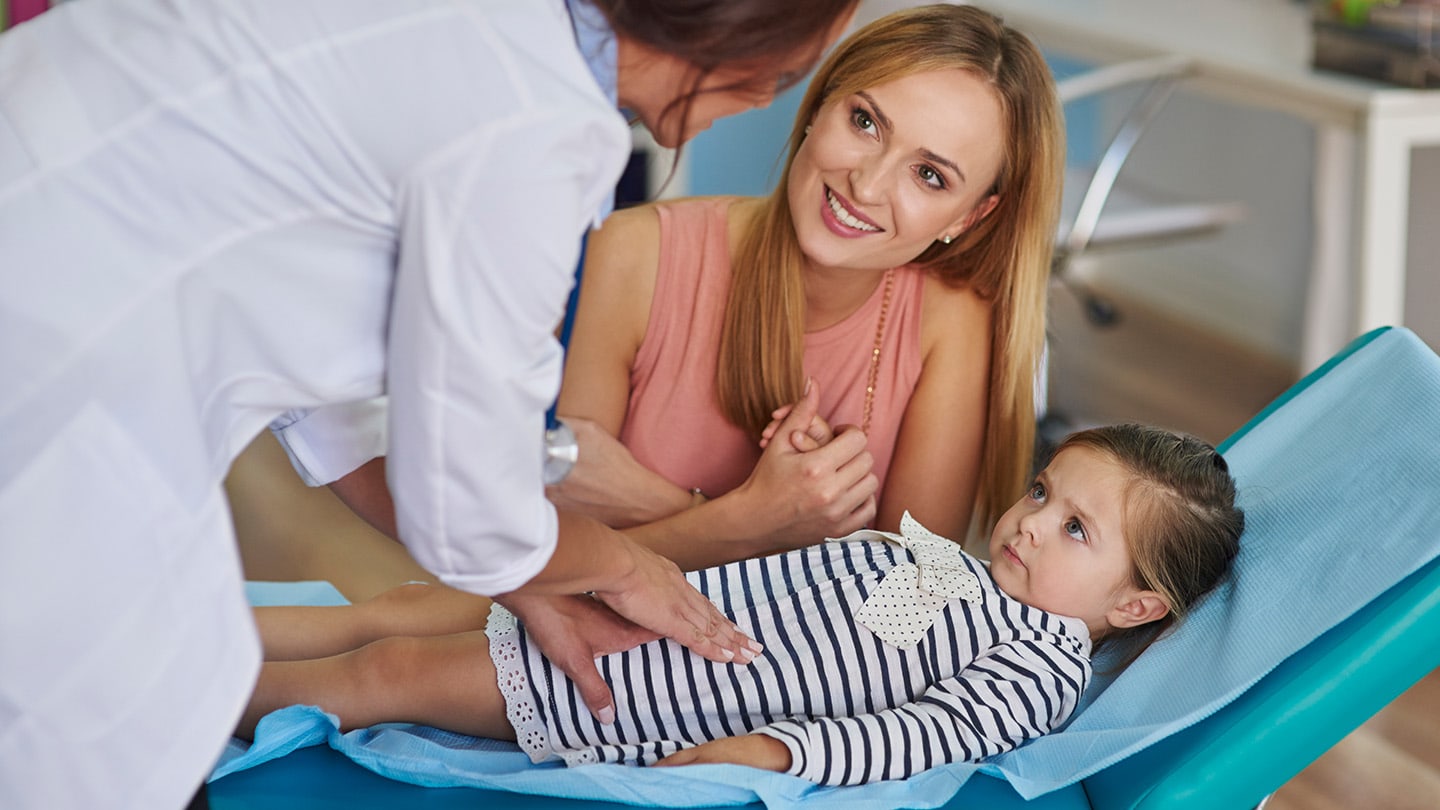 Clinician examining a child with a parent nearby.