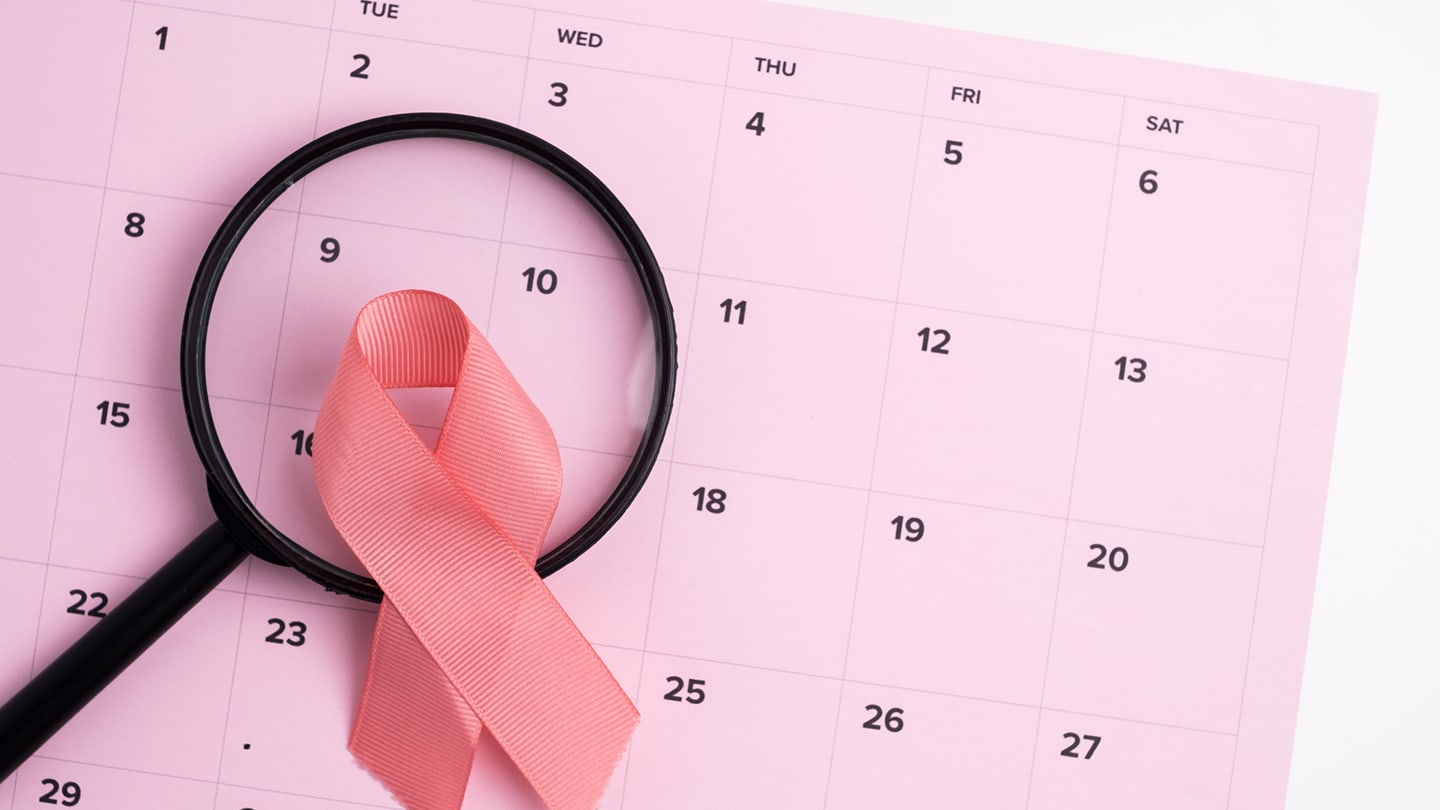 Pink breast cancer awareness ribbon on a calendar.