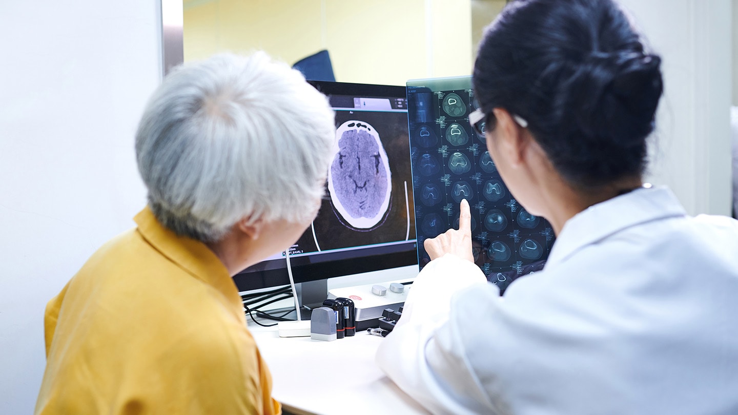 Clinician and patient reviewing brain scans on a monitor.