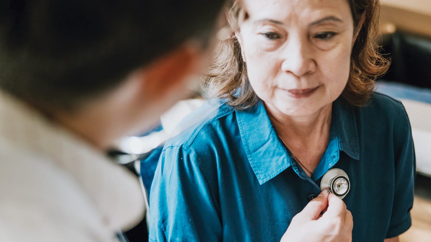 Clinician using a stethoscope during a patient consultation.
