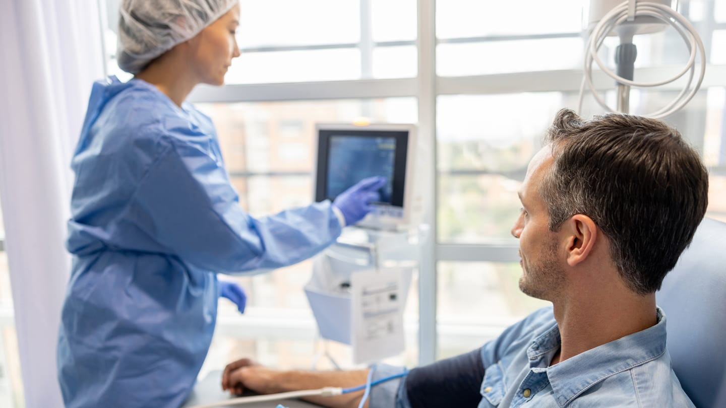 Patient seated for treatment while a clinician adjusts equipment.