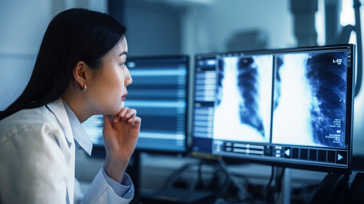 Radiologist reviewing lung scans on computer monitors.