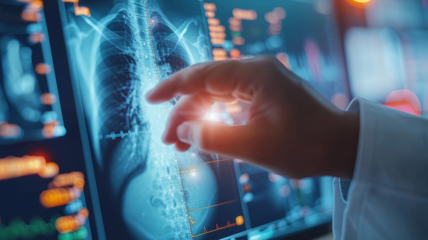 Hand using a digital display with chest imaging and clinical data.