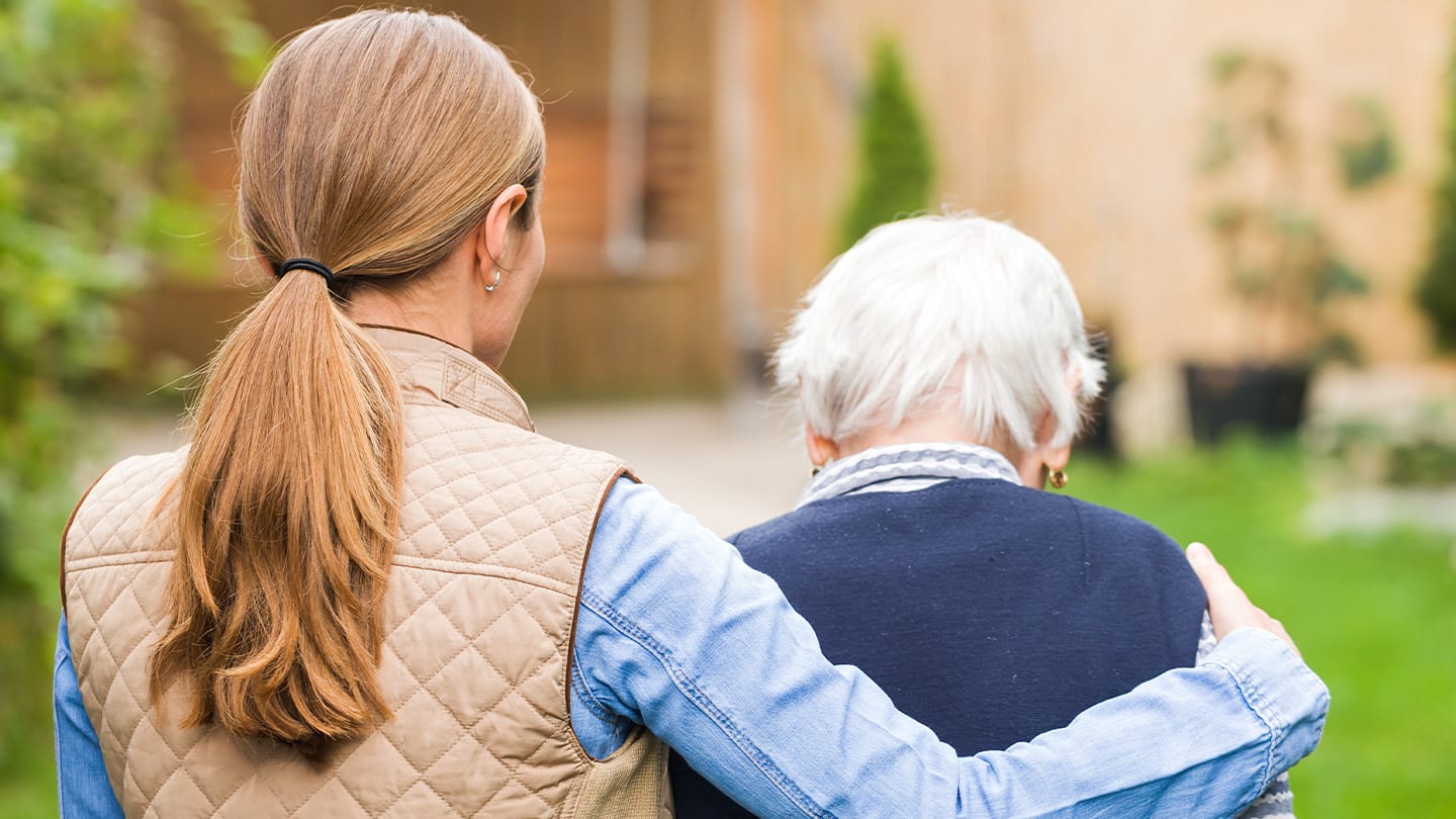 Caregiver walking outdoors with an older adult.