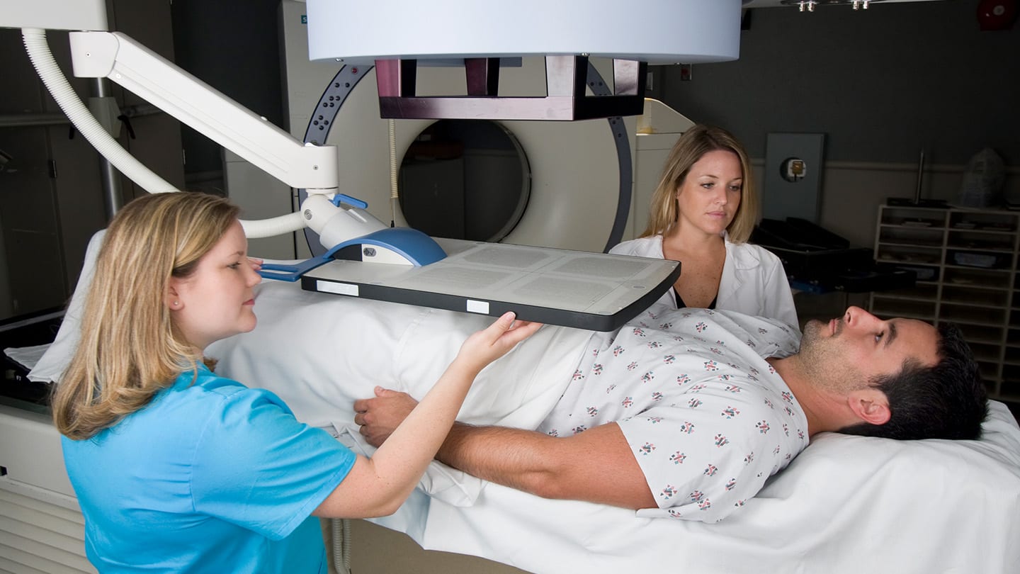 Clinicians positioning a patient for image-guided treatment.