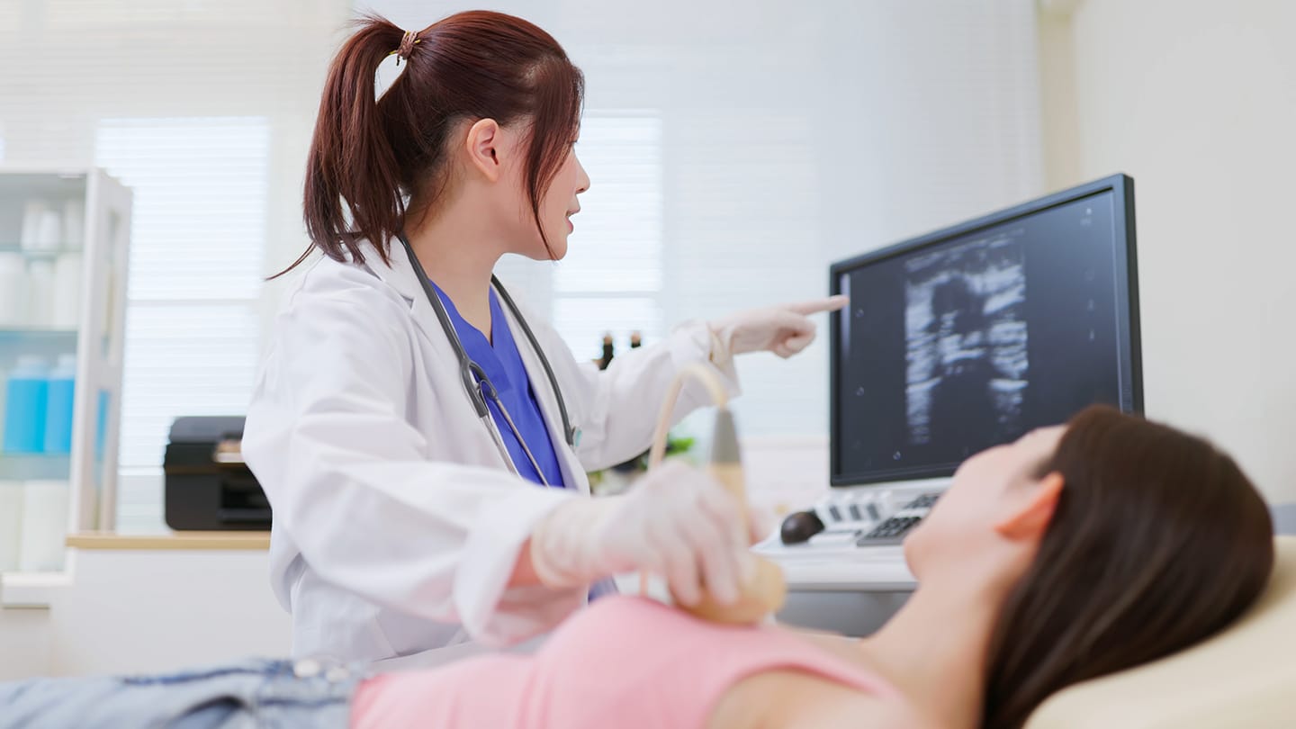 Clinician performing breast imaging on a patient.