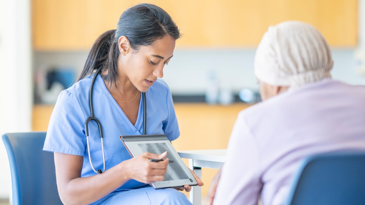 Clinician speaking with a patient during an oncology visit.