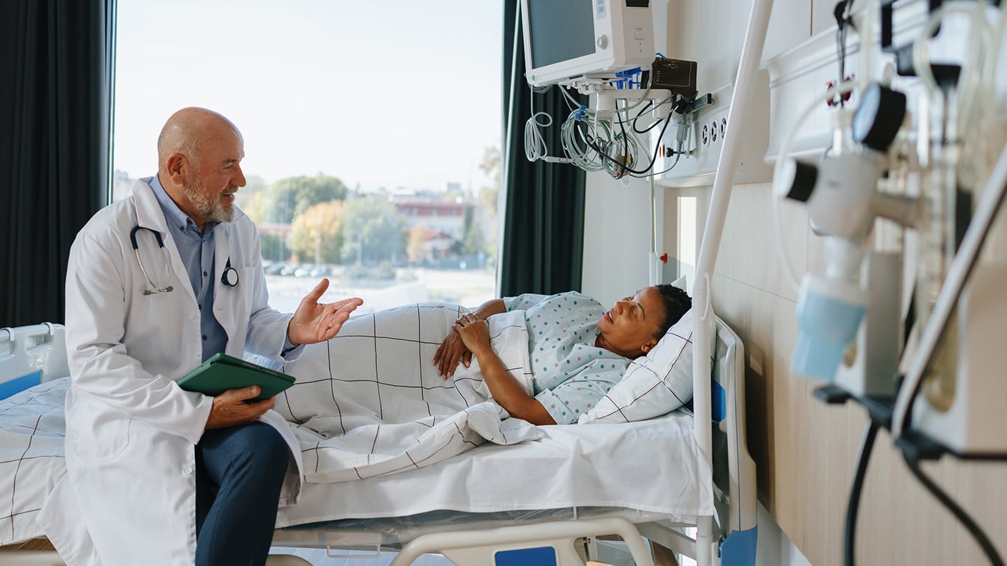 Doctor speaking with a patient in a hospital bed.