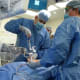 Nicholas Theodore, in an operating room wearing a surgical gown, camp and gloves, performs a robotic spine surgery