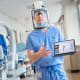 doctor in surgical attire holding a tablet showing a shoulder replacement device