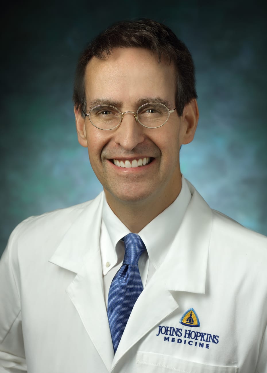  James Gammie, in a formal portrait, wearing a white lab coat, white button down shirt and blue tie.