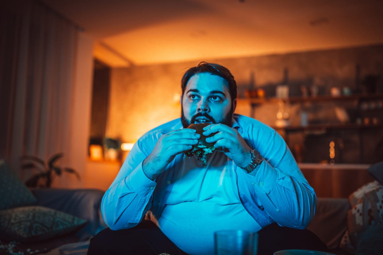 guy-watching-tv-and-eating-hamburger