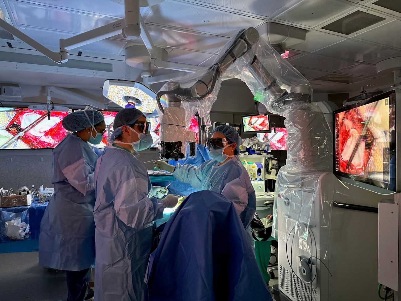 Neurosurgeon Judy Huang, along with a resident and tech, use a robotic exoscope to perform surgery in an operating room