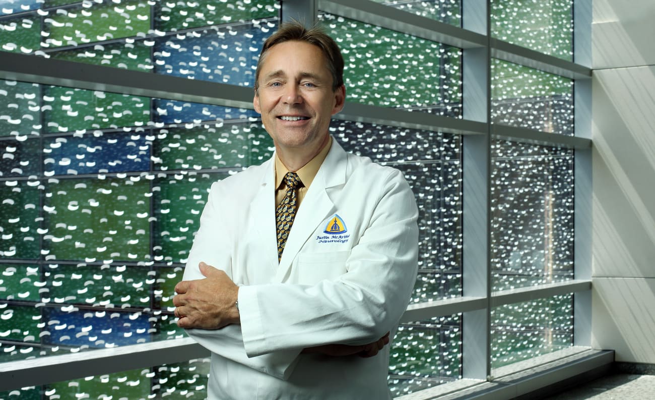 Dr. Justin McArthur stands by windows at The Johns Hopkins Hospital in a traditional white lab coat.