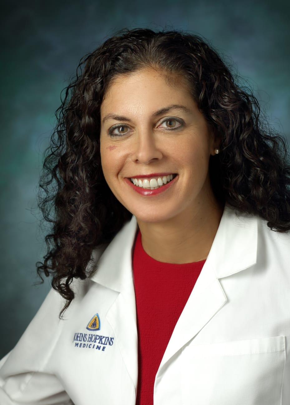 Lilah Morris-Wiseman in a formal portrait wearing a white lab coat, red blouse and pearl earrings