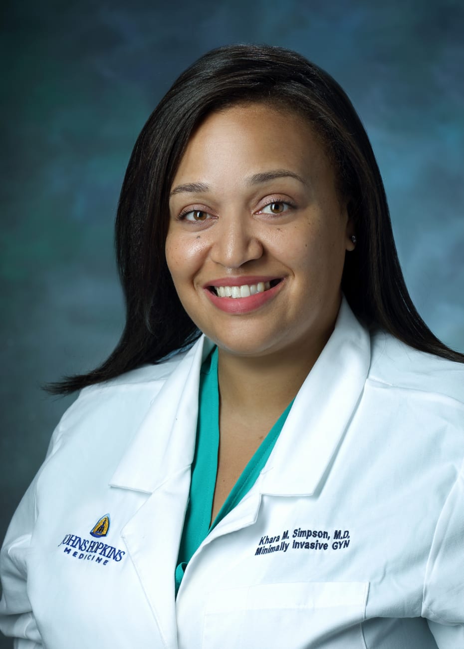 Gynecological surgeon Khara Simpson, in a formal portrait, wearing a white lab coat and turquoise blouse