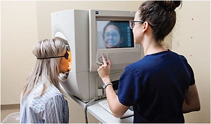 Liz Williams, BA (right), performs a visual field test.