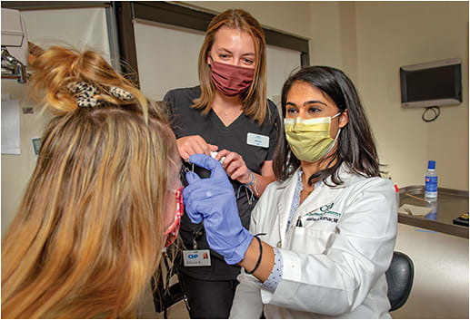 Alisha G. Kumar, MD, inserts a speculum as Allison Kramer, OSC, ophthalmic technician, assists.