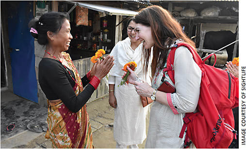 Following prevention program refresher training, SightLife Advocate Audrey Talley Rostov, MD, is greeted by a community health worker in her home. Behind her is Mridula Singh, SightLife Clinical Programs consultant.