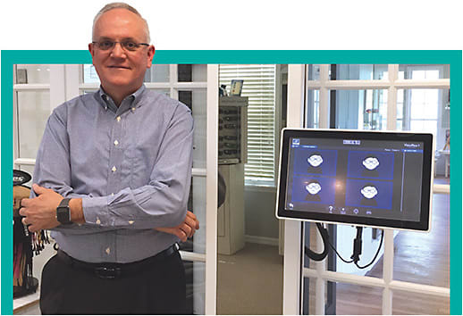 Optician Tom Parrish stands in his optical with the Visioffice 2 from Essilor, one of the many high-tech tools available today to ECPs to expand the patient experience.