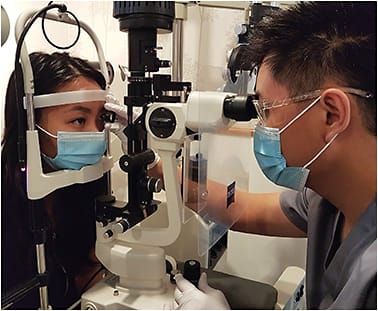 Figure 1. An example of current slit lamp examination precautions: face mask for patient, PPE for practitioner, breath shield, and minimal talking.