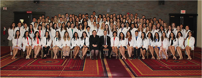 NECO President Howard Purcell, O.D., and Sandra Mohr, EdD, Dean of Academic Resources and Administration (center) with the Class of 2020 at the White Coat Ceremony.