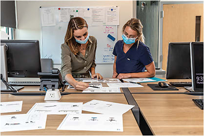 Reviewing site plans to ensure maximum patient efficiency for Colorado Retina’s next Lean office buildout in Lakewood, CO, are Kendall Johnson, marketing manager (left), and Savannah Johnson, ophthalmic technician.